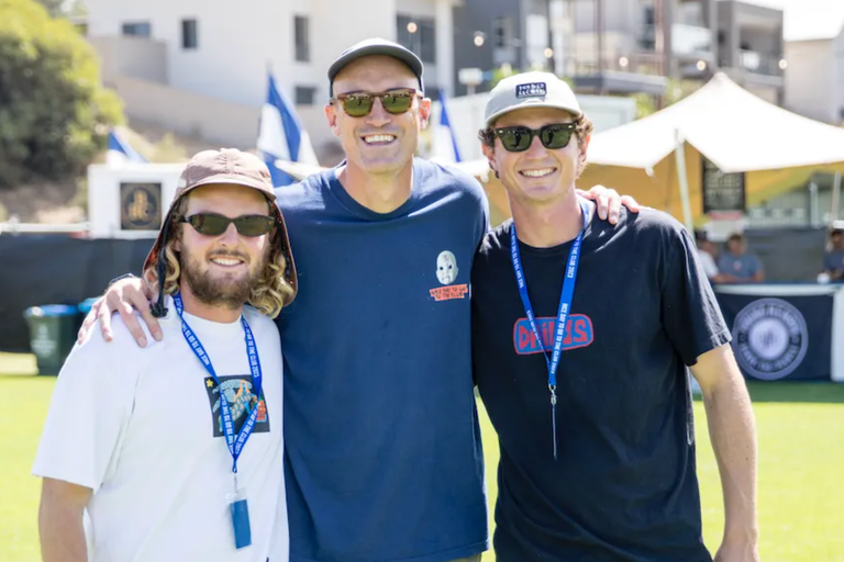 Ryan Fitzgerald posing with Tom Redden and Jack Stokes of Daybed Records in sunglasses and caps at an outdoor music festival promo event.